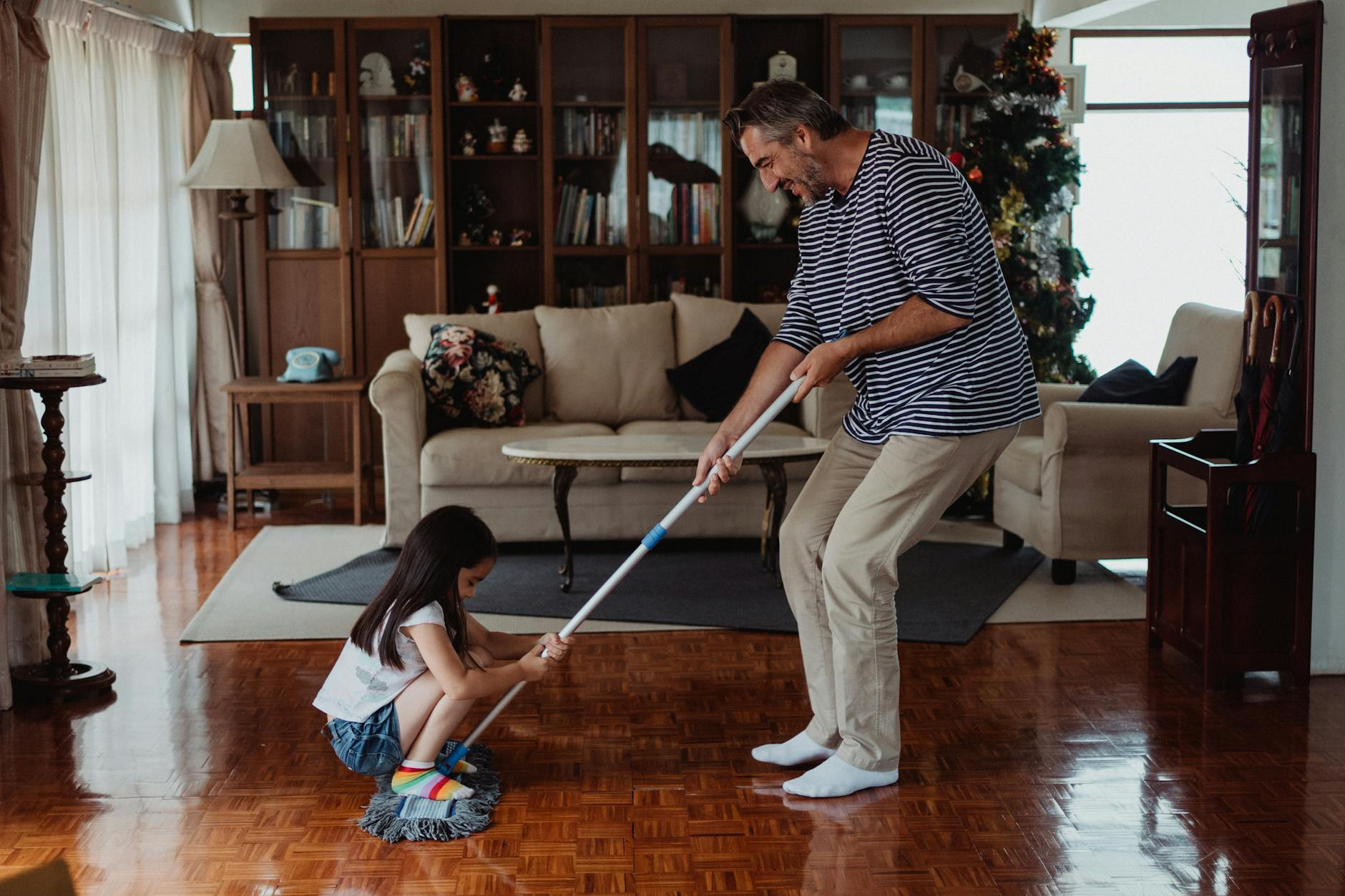 father and daughter playing with a mop in the living room